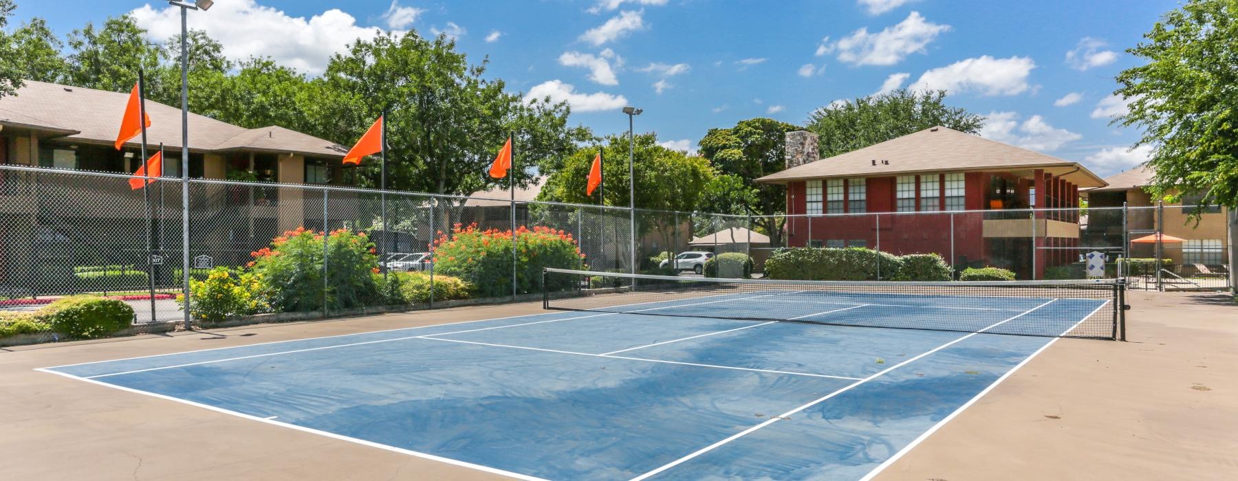 a tennis court with a fence and trees in the background